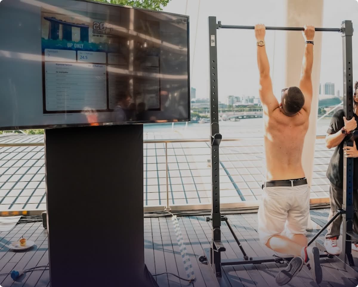 Excited participant at TOKEN2049 conference in Singapore, hanging from pull-up bar