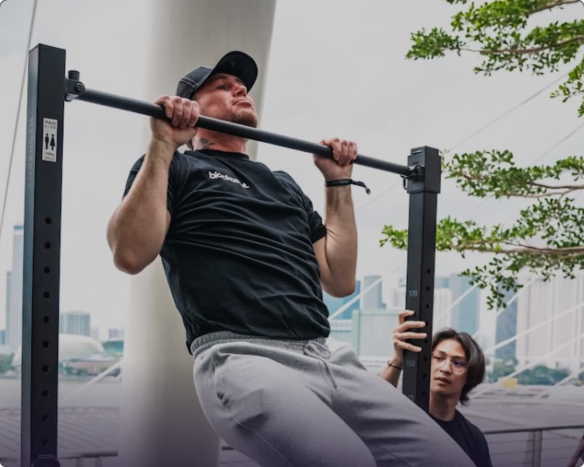 Excited participant at TOKEN2049 conference in Singapore, hanging from pull-up bar